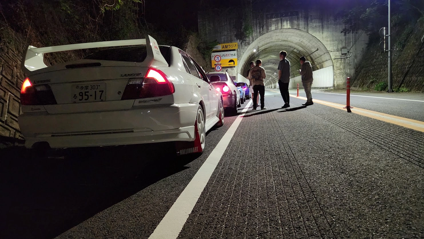 トンネルの外に停めたクルマとドライバーたち