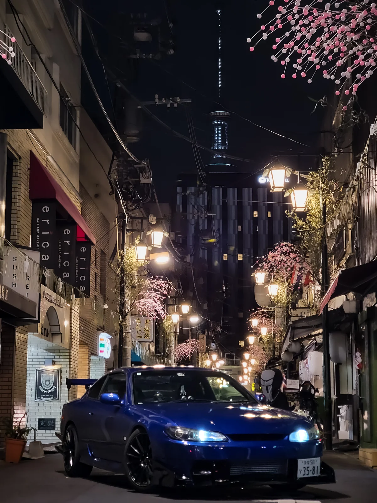 夜の細い街路に停まる青いクーペ